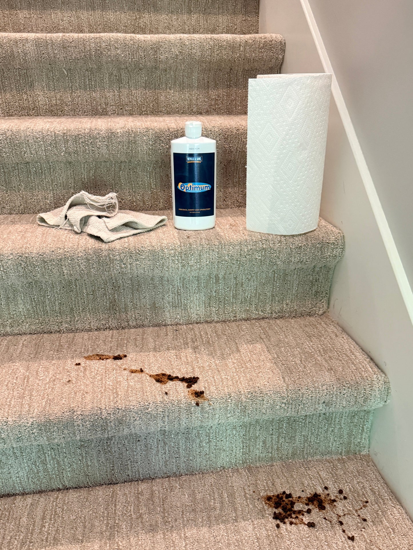 Textured curtains with a bottle of cleaning solution and a cloth on top, showing a stain.