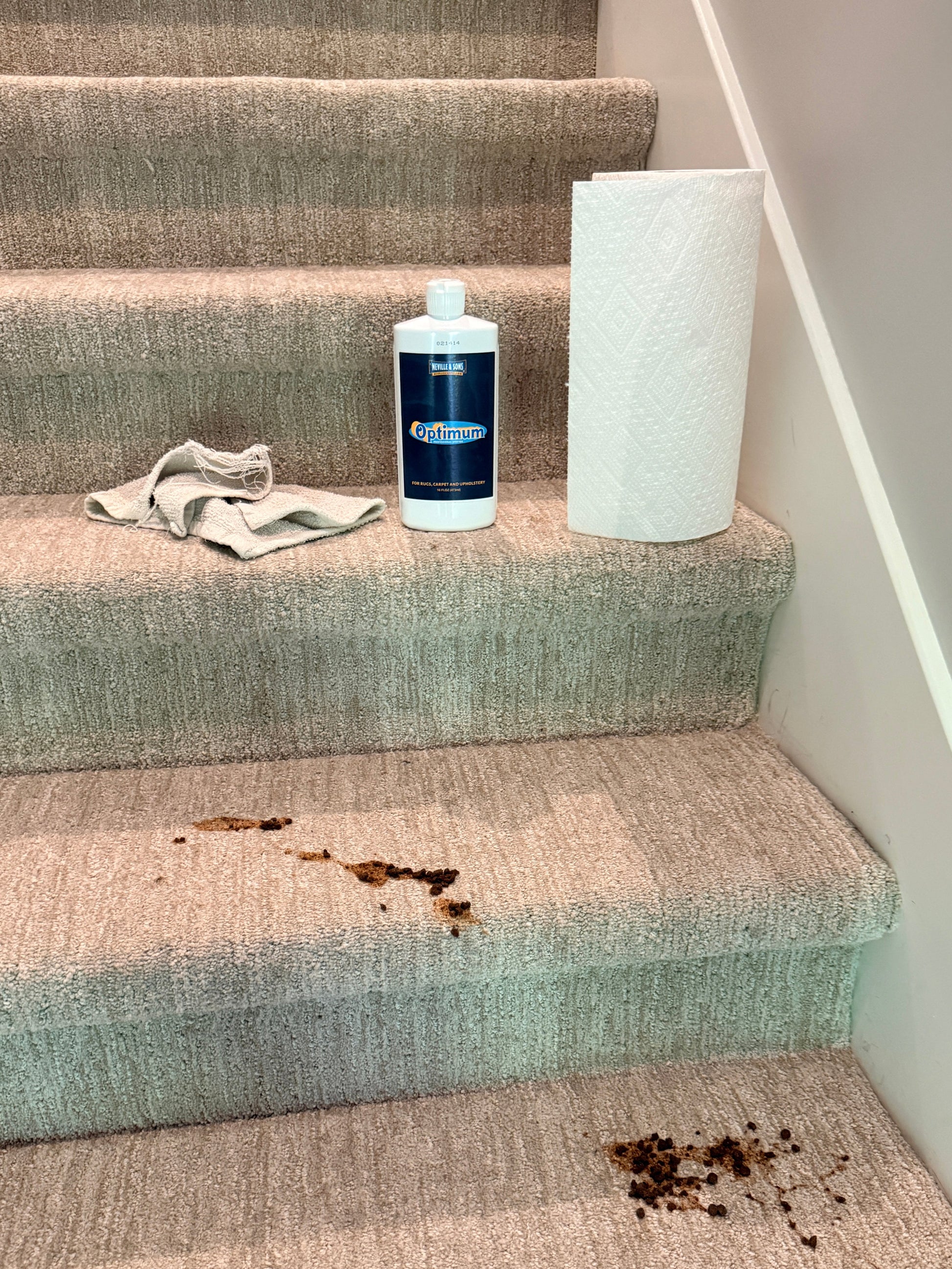 Textured curtains with a bottle of cleaning solution and a cloth on top, showing a stain.
